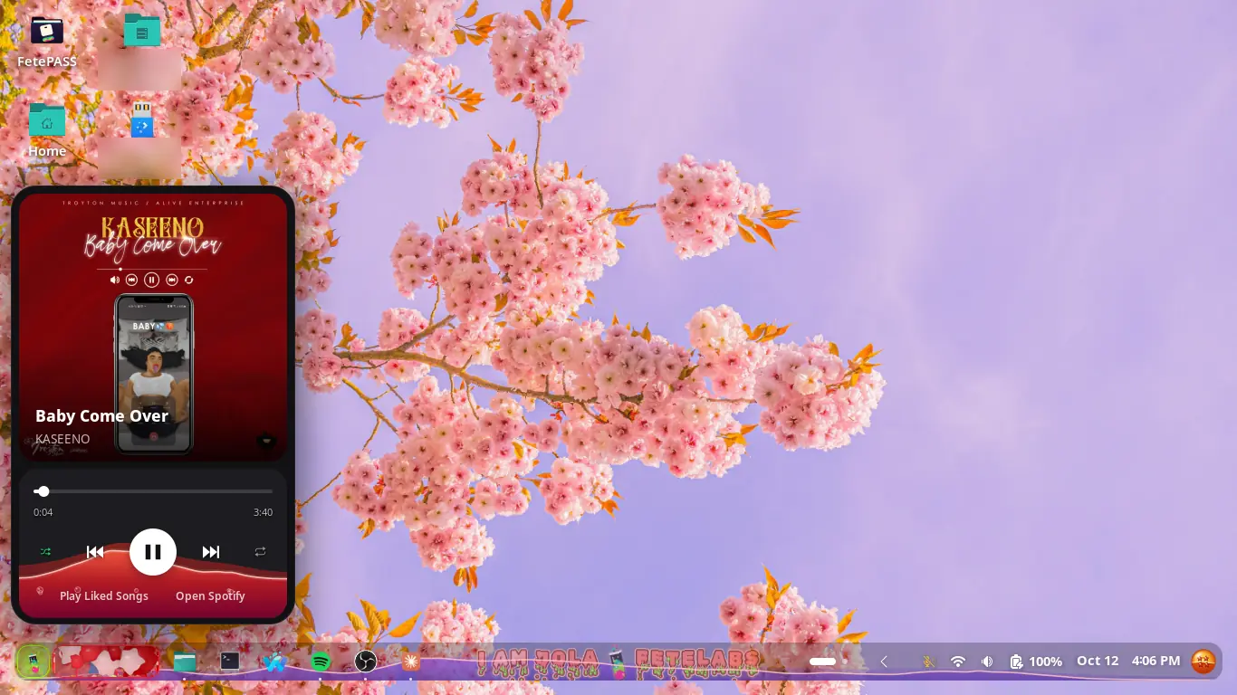 A GNOME desktop under pink cherry blossom with Fetelabs Task Bar: the mini player open at the left with the album cover, a seek bar and the controls floating on red water, and the bar’s player controls turned into a red paint splash